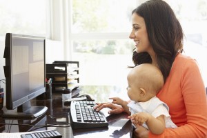 Mother typing on a computer with a baby in her lap